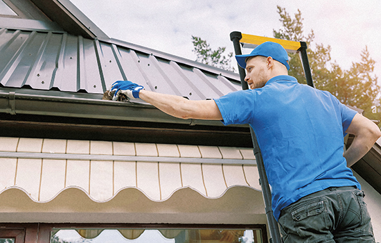 商人は伸縮 アルミ はしごで家の屋根を修理しています。